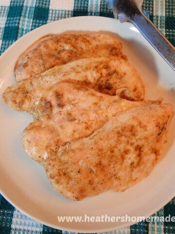 Top view of layered Baked Cumin Chicken breasts with tongs.