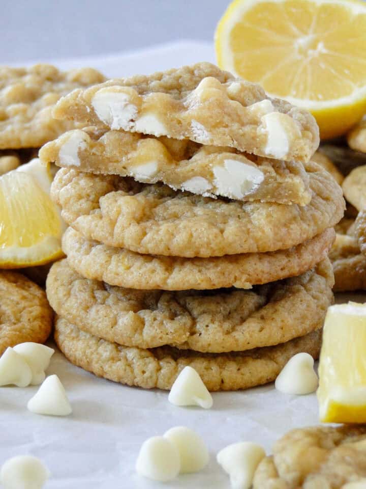Side view of 5 lemon white chocolate cookies stacked with top cookie cut in half showing center of cookie.