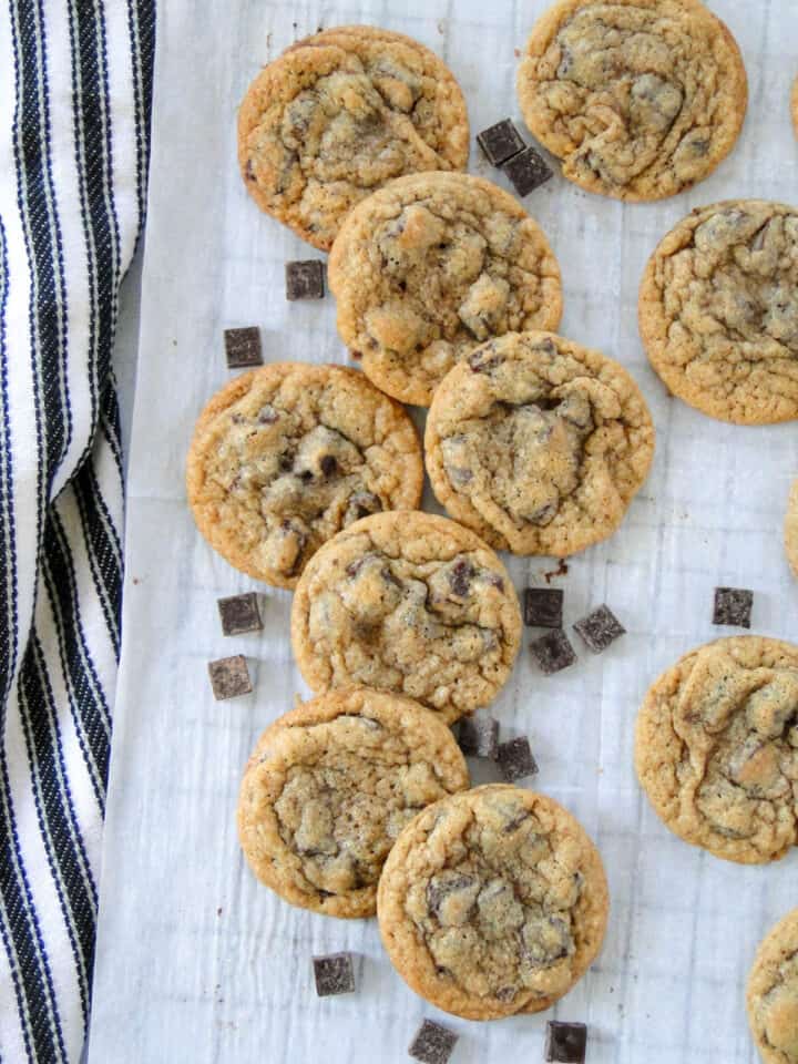 Chocolate chunk cookies staggered in a column with extra chocolate chunks sprinkled around.