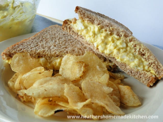 Classic Egg Salad in bread on plate with potato chips. 