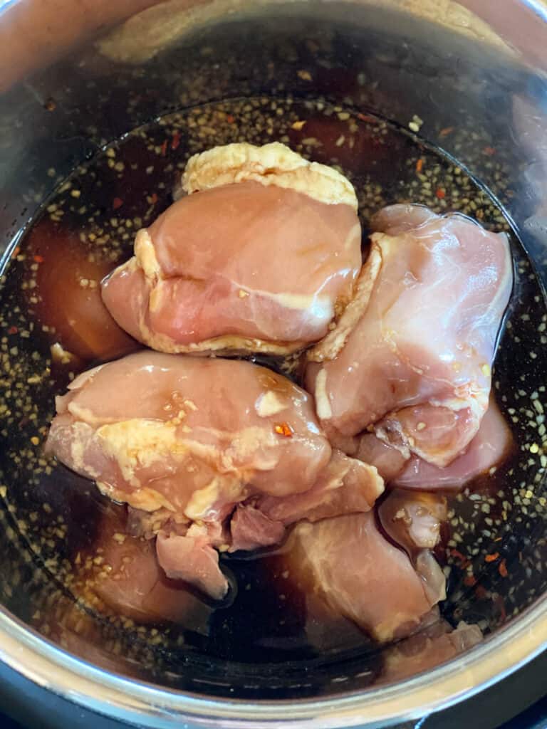 Teriyaki sauce poured over chicken thighs in instant pot.