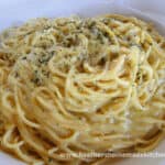 Front view of large white bowl of Classic Spaghetti Carbonara with parsley and black pepper on top of pasta.