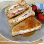 Front view of Strawberries & Cream Stuffed French Toast cut in half and drizzled with syrup.