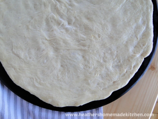 Close up view of Homemade Pizza Dough spread on pizza stone. 