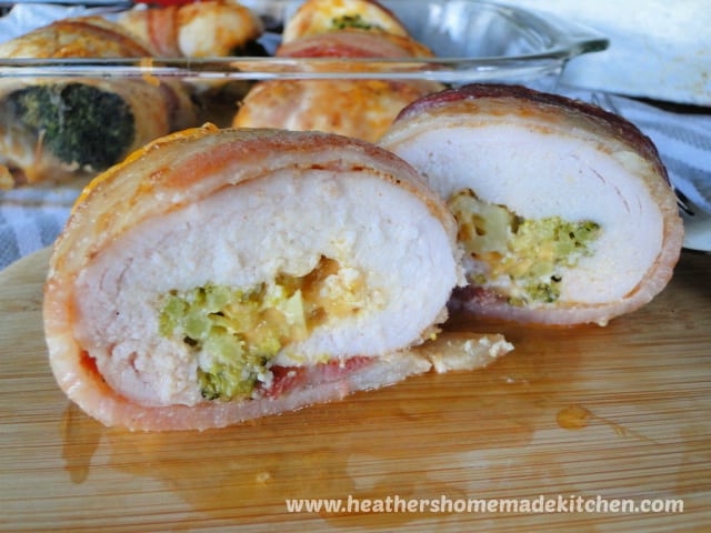 Bacon Wrapped Cheesy Broccoli Chicken sliced in half on bamboo bored.