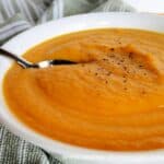 Creamy Carrot Soup in white bowl with spoon.