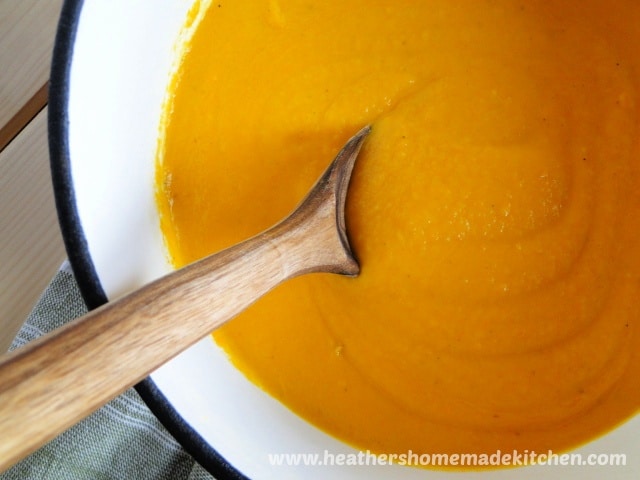 Creamy Carrot Soup in pot with wooden spoon.