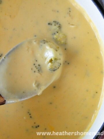 Cheesy Broccoli Soup in pot with wooden spoon.