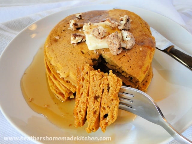 Close up view of bite of Whole Wheat Pumpkin Pancakes on fork with butter, pecans and maple syrup.