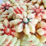 Spritz Butter Cookies shaped as green trees and white flowers and sprinkled with green and red sugar.