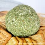 Holiday Cheese Ball covered in green parsley surrounded by an assortment of crackers.