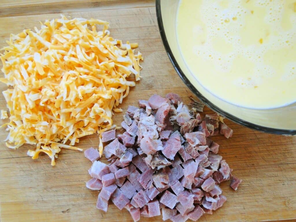 Wet ingredients, shredded cheese, and diced ham for best ever egg bake.