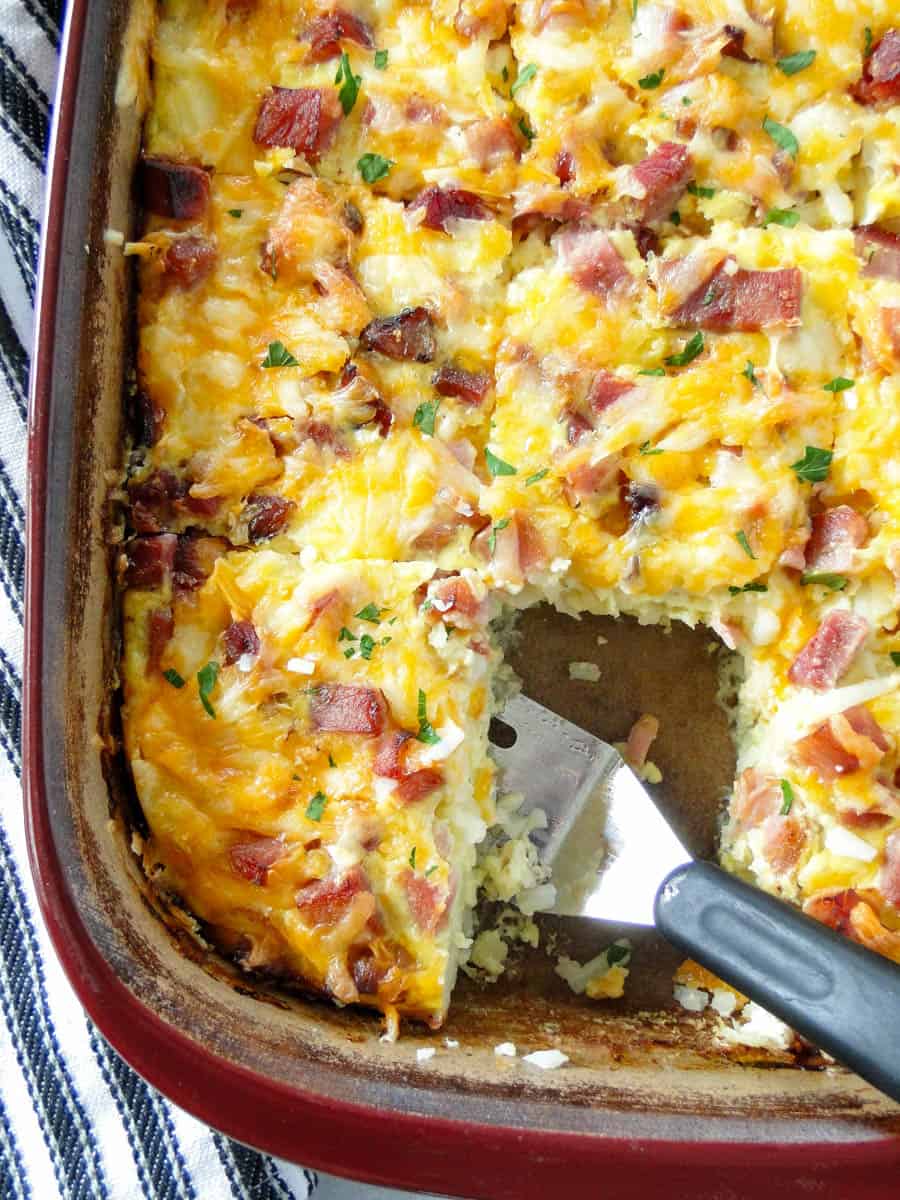 Top view of egg bake casserole in baking dish with one piece out and spatula under another piece.