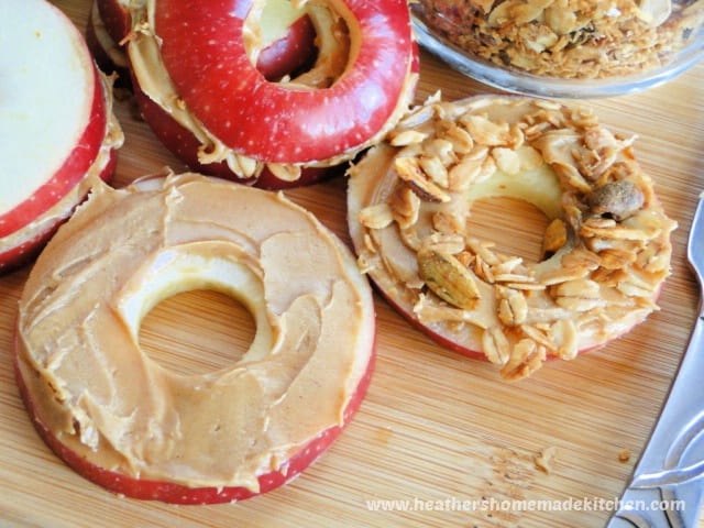 Apple slices with peanut butter and one topped with granola. 