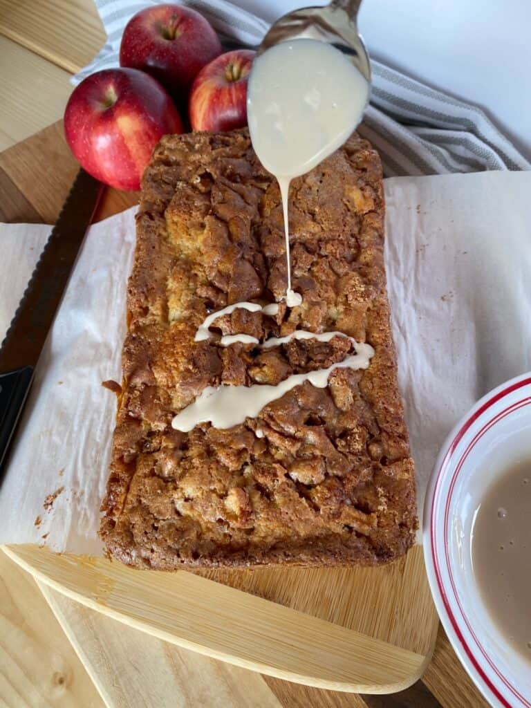 Apple fritter loaf being drizzled with maple glaze. 