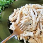 Instant pot shredded chicken on green plate with fork and chicken on fork.