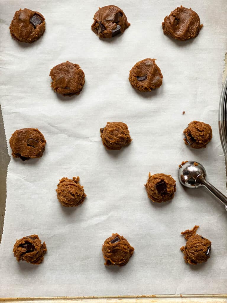 Cookie dough scooped on parchment lined cookie sheet.