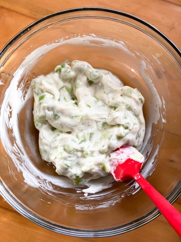 Salad dressing ingredients combined in glass bowl.