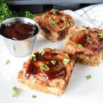 Mini bbq turkey meatloaves on square with plate with extra bbq sauce in sauce cup.