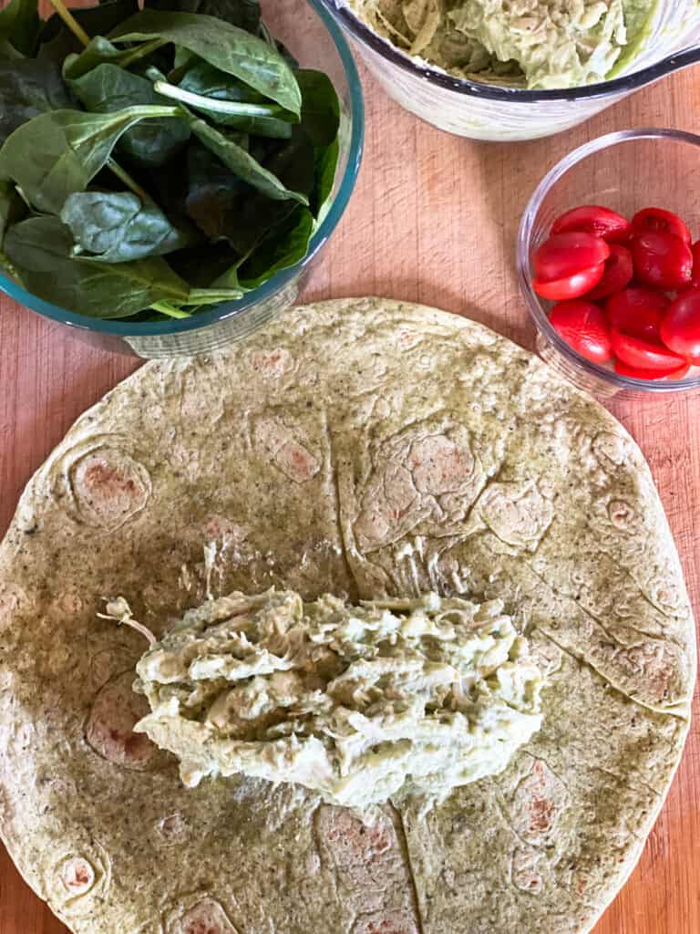 Chicken avocado salad on top of tortilla.