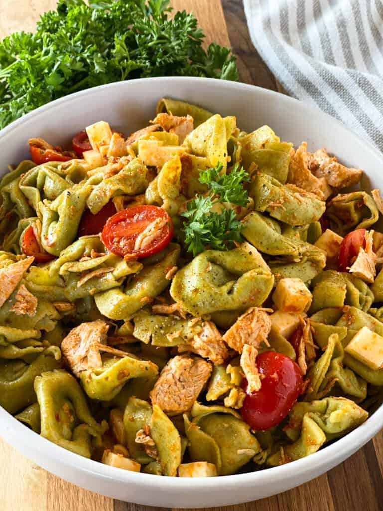 Top view of chicken tortellini salad in white round bowl. 