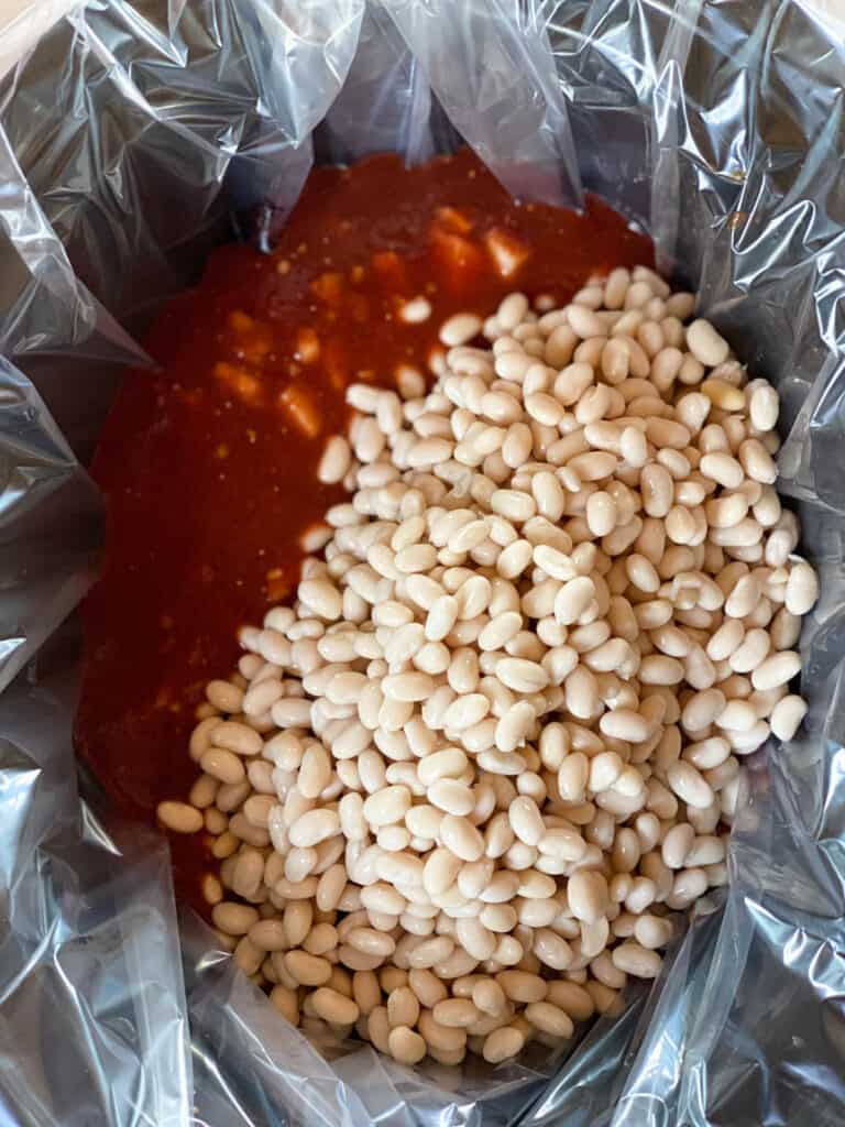 Sauce added to crock with soaked beans on top.
