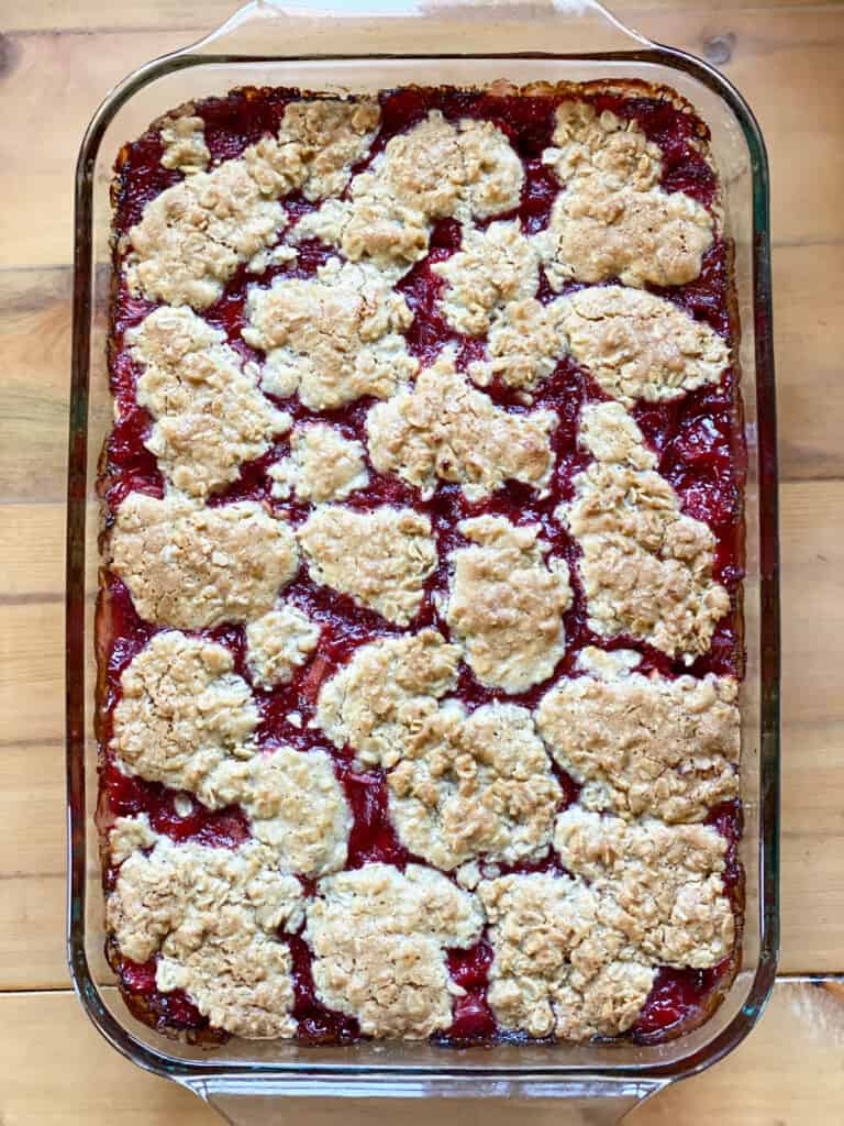 Strawberry rhubarb bars baked and cooling in 9x13 glass baking dish.