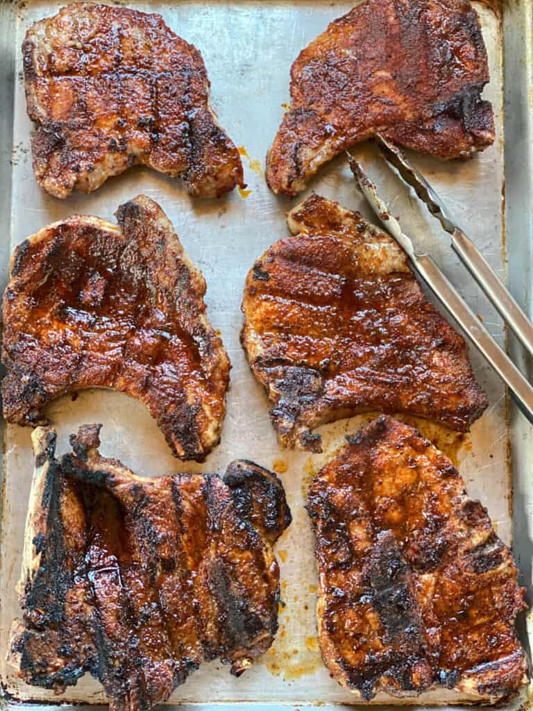 Fully cooked grilled pork chops on sheet pan.