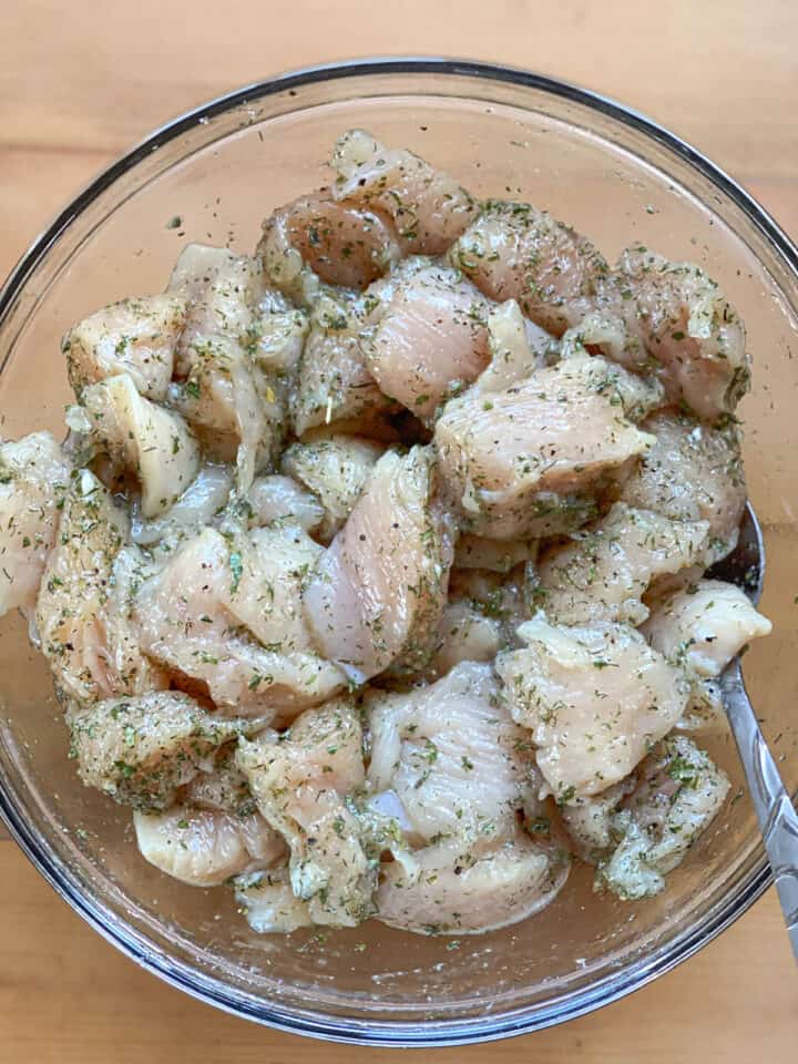 Cut chicken breasts mixed with ranch seasoning in large glass bowl.