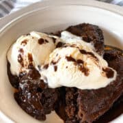 Crock pot chocolate lava cake dished into a white bowl topped with vanilla ice cream.