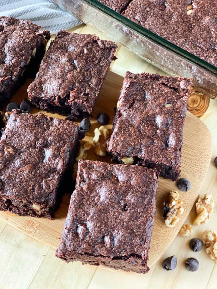 Top view of dark chocolate walnut brownie squares on board.