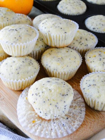 Meyer Lemon Poppy Seed Muffins on board with paper liner off of one muffin.