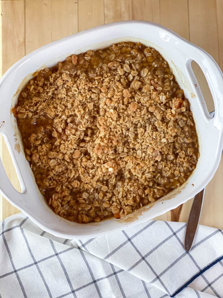 Top view of baked peach crisp in white baking dish.