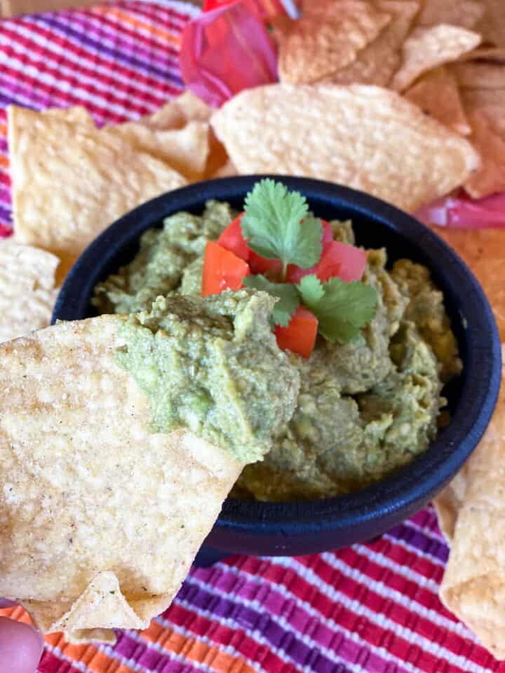 Tortilla chip being dipped into homemade guacamole.