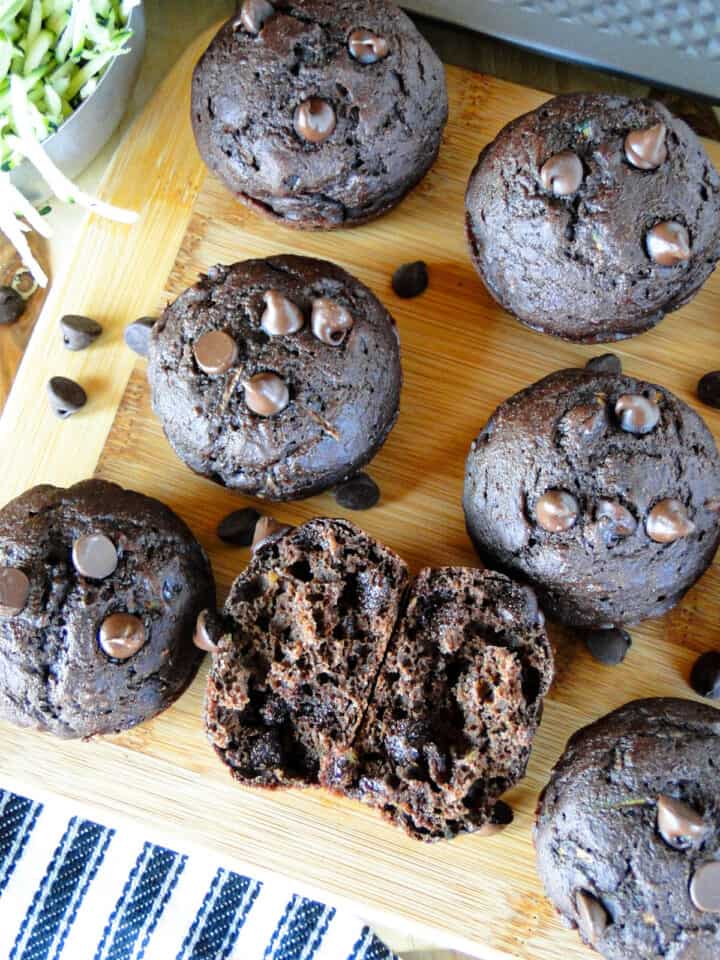 Healthy double chocolate zucchini muffins with one muffin broken in half showing inside of muffin.