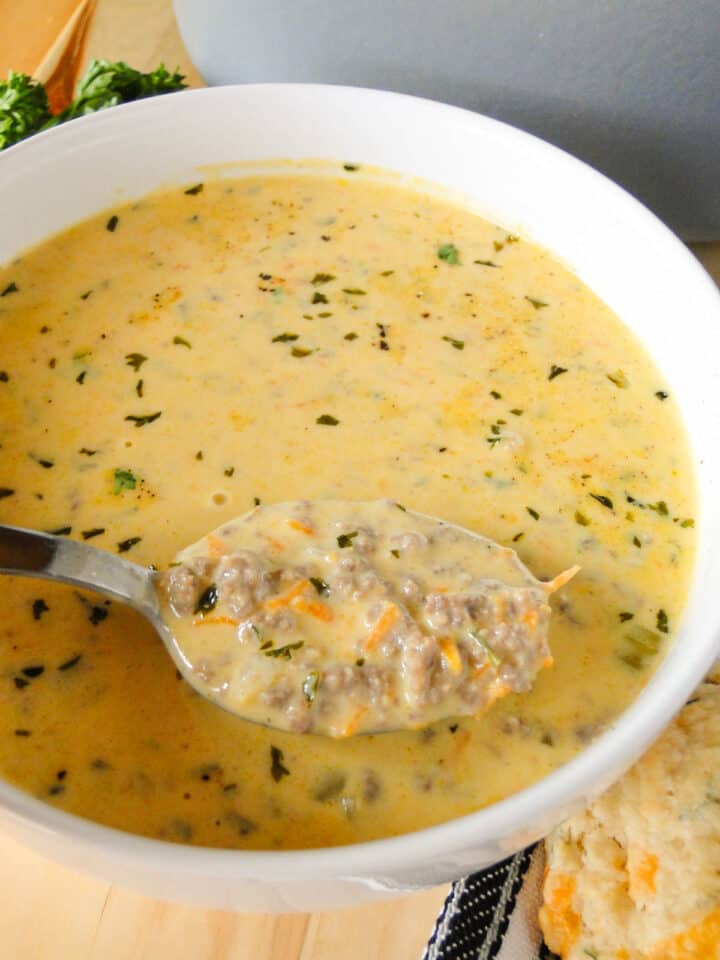 Spoonful of easy cheeseburger soup in a white round bowl.