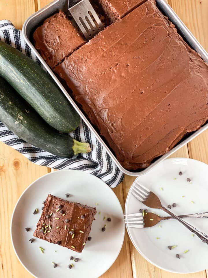 Top view of chocolate zucchini cake in pan with slice on plate.