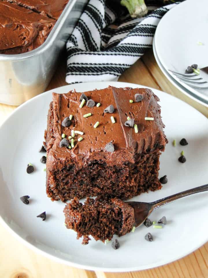 Chocolate zucchini cake slice on plate with bite on fork. 