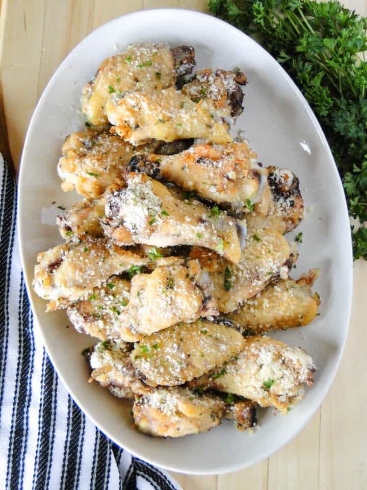 Top view of crock pot garlic parmesan chicken wings on white oval platter.