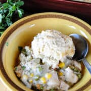 Bowlful of easy chicken pot pie with biscuits and spoon.