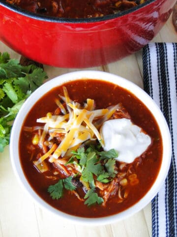 Top view of easy chicken taco soup topped with shredded cheese, sour cream and cilantro.