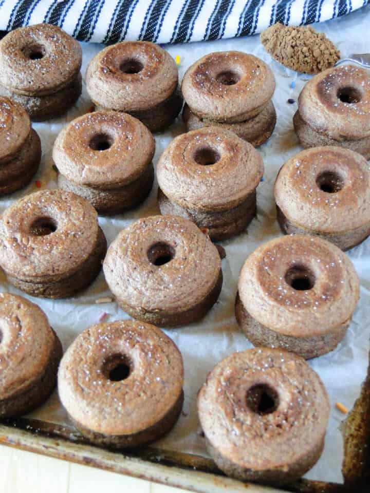 Chocolate mini donuts in rows on sheet pan.