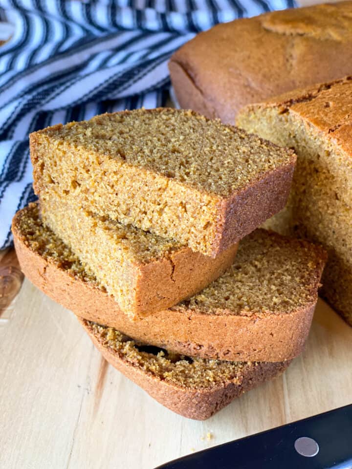 Easy pumpkin bread slices stacked in front of pumpkin bread loaf.
