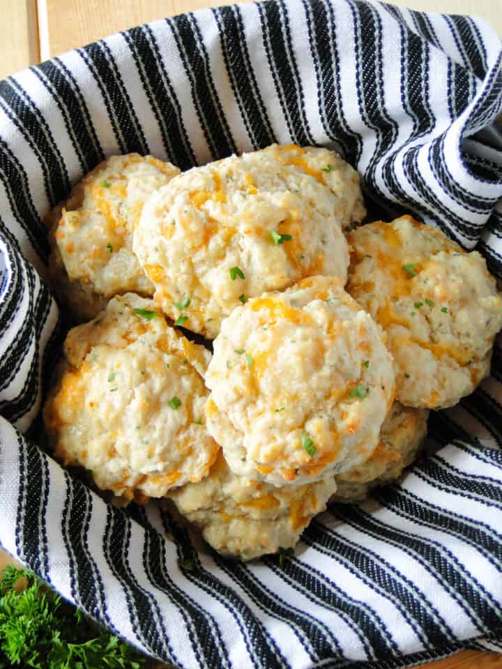 Basket lined with towel full of garlic cheese drop biscuits.