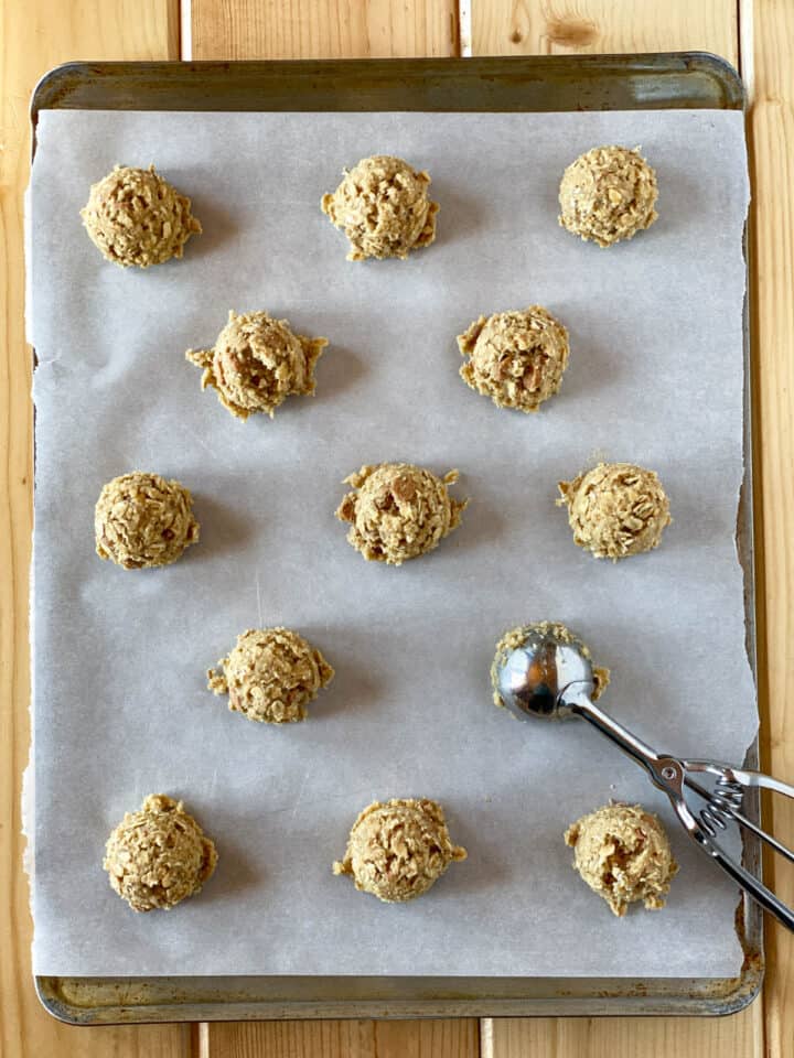 Cookie dough on cookie sheet with cookie scoop.