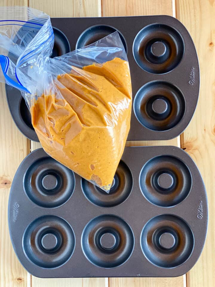 Donut batter in bag by donut pans ready to be piped in pans.