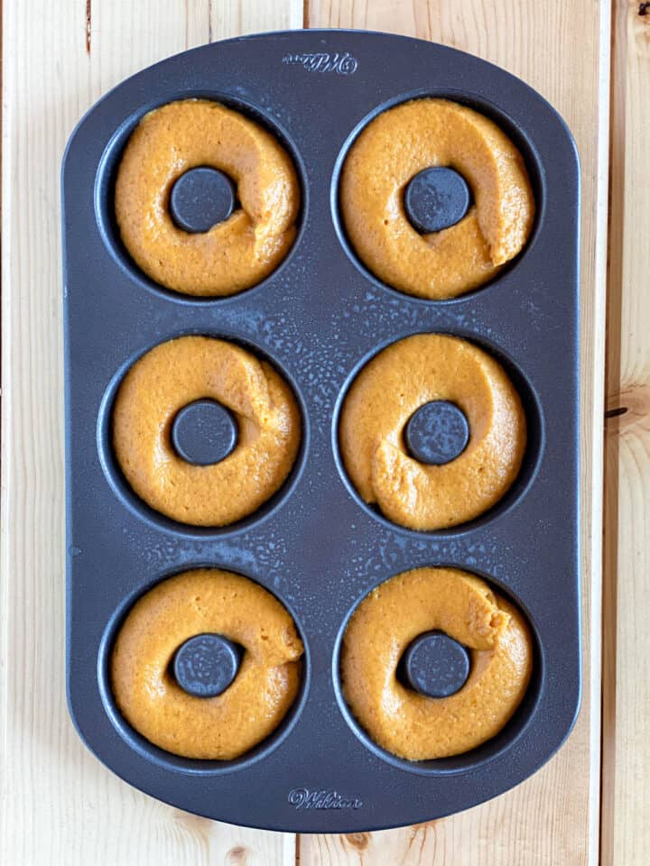 Pumpkin donut batter piped into donut pans.