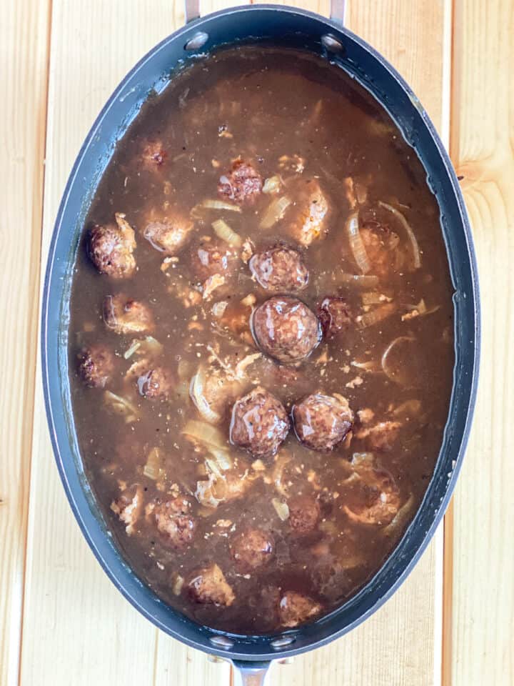 Salisbury steak meatballs in onion gravy in large oval skillet.