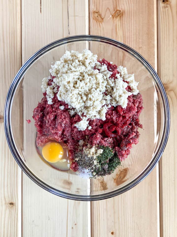 All meatball ingredients in large glass bowl.