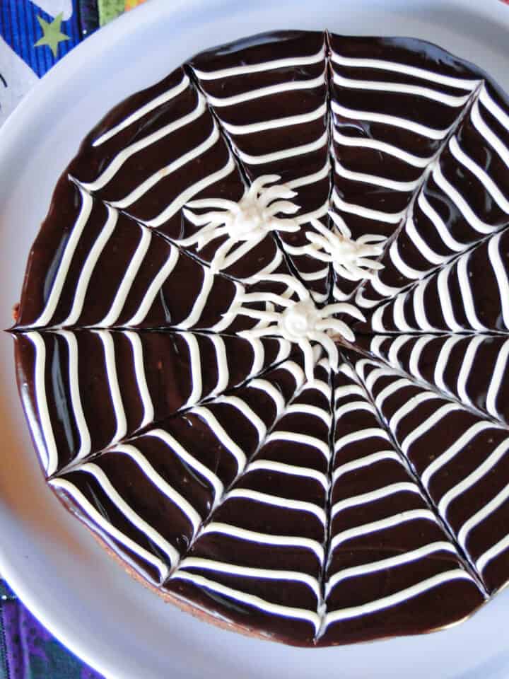 Close top view of spiderweb brownies on white round cake plate.